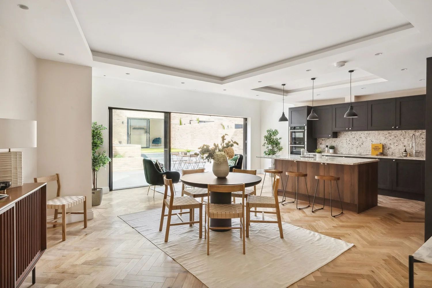 Open-plan kitchen and dining room with herringbone oak floor and sliding doors to the garden