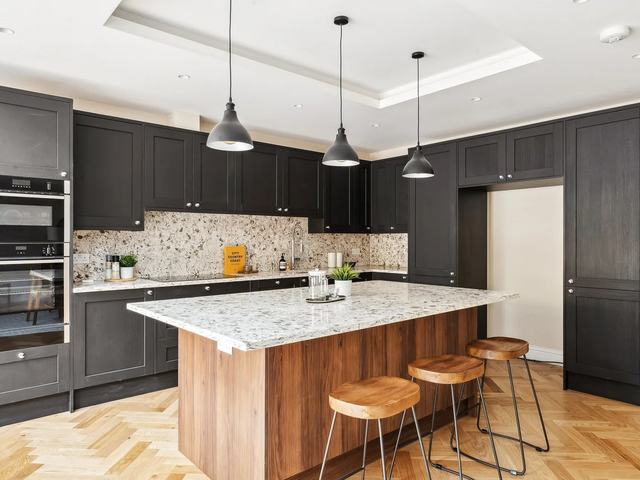 Dark shaker-style kitchen with a timber-clad island and stone worktops