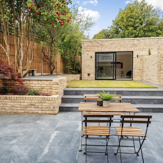 Brick garden building with glazed doors at the end of a terraced garden