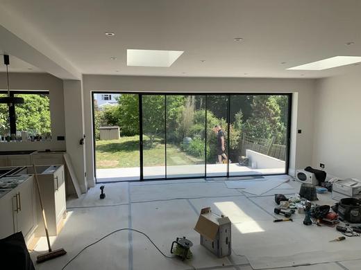 Open-plan room with wide sliding doors and roof lights, during the build