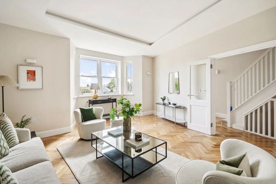 Bright living room with herringbone oak flooring, bay window and staircase beyond