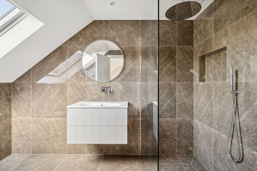 Loft shower room with stone-effect wall tiles, wall-hung basin and walk-in shower