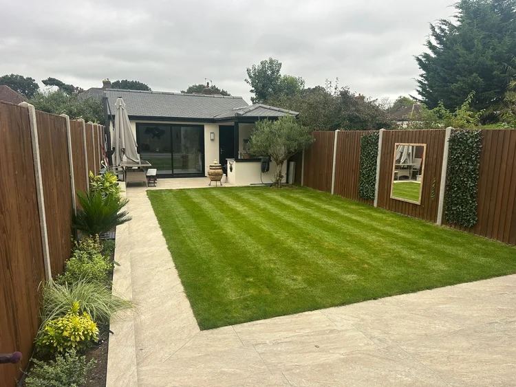 Rendered garden building with sliding doors, new lawn and stone paving