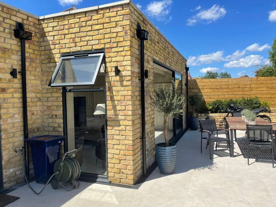 Yellow-brick single-storey extension with glazed doors opening onto a paved patio