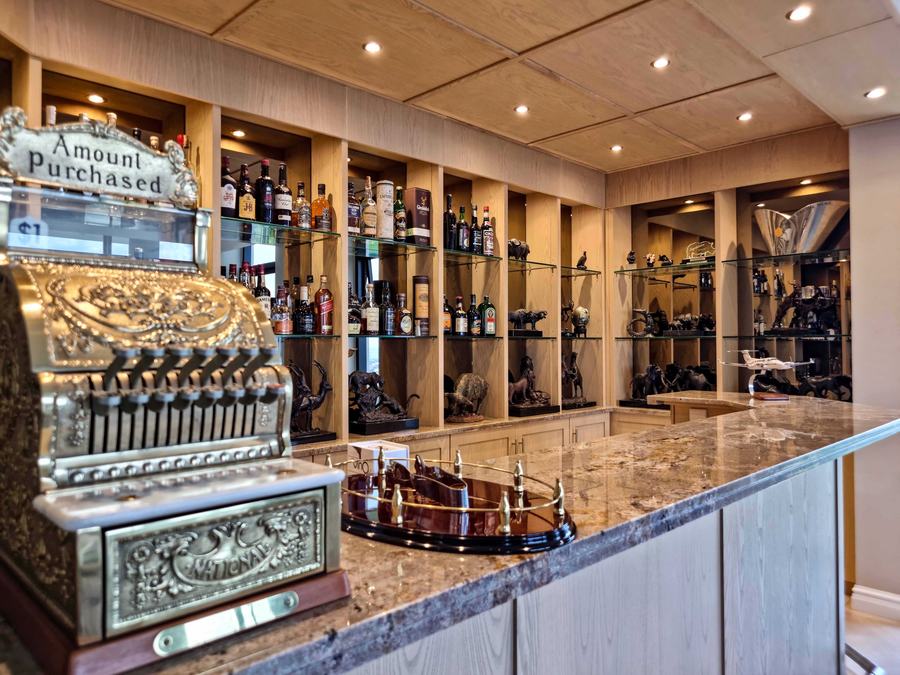 Bar with pale timber shelving, a panelled ceiling with downlights and a granite counter