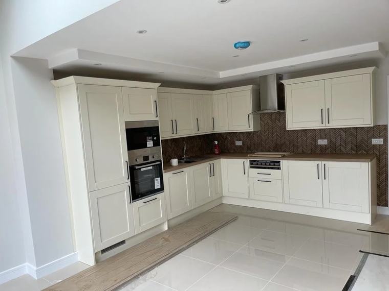 Newly fitted kitchen with cream units and a tiled floor in an empty property